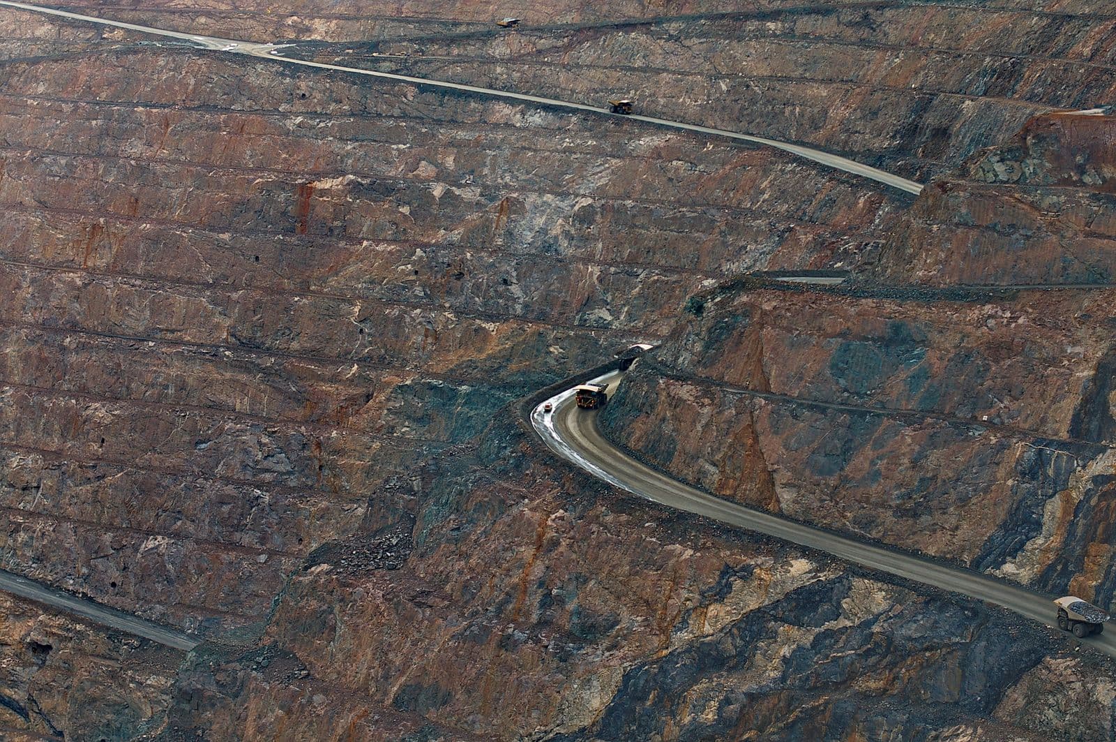Aerial view of haul trucks on a winding haul road in an open-pit mine